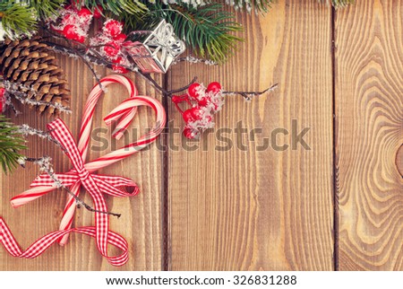 Christmas tree branch with snow and candy canes on wooden table. Top view with copy space. Toned
