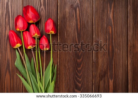 Red tulips bouquet over wooden table background with copy space