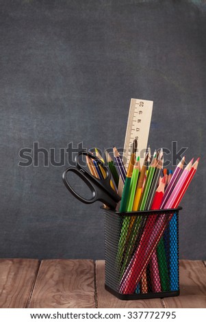 School and office supplies on classroom table in front of blackboard. View with copy space