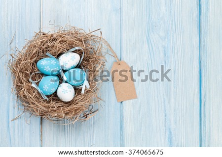 Easter eggs in nest over wooden background. View with copy space