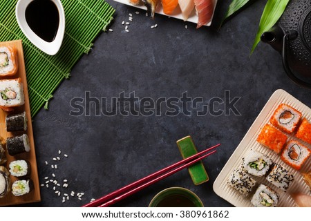 Set of sushi and maki roll and green tea over stone table. Top view with copy space