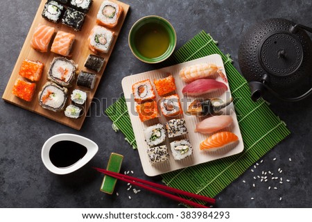 Set of sushi and maki roll and green tea on stone table. Top view