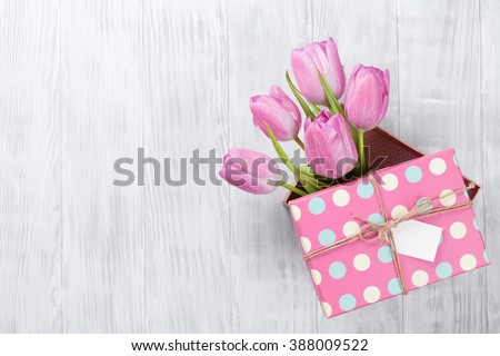 Fresh pink tulip flowers in gift box on wooden table. Top view with copy space