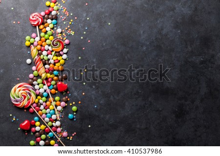 Colorful candies and lollipops over stone background. Top view with copy space