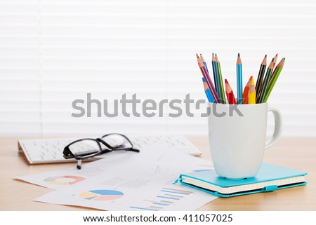 Office workplace with supplies on wood desk table in front of window with blinds