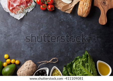 Ciabatta sandwich cooking with romaine salad, prosciutto and mozzarella cheese over stone background. Top view with copy space