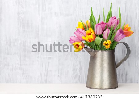 Fresh colorful tulip flowers bouquet on shelf in front of wooden wall