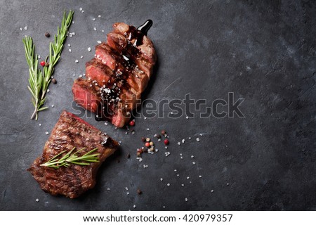 Grilled striploin sliced steak with salt and pepper over stone table. Top view with copy space