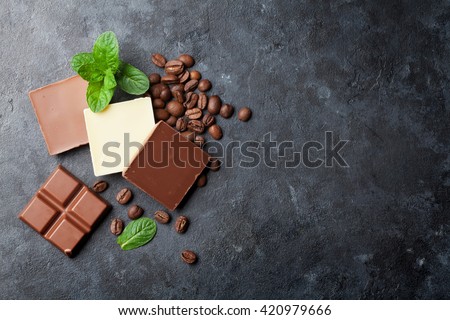 Chocolate and coffee beans on dark stone table. Top view with copy space