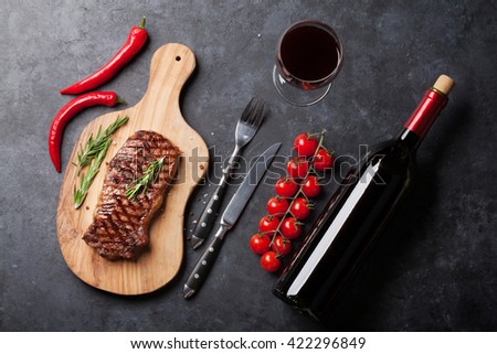 Grilled striploin sliced steak and red wine over stone table. Top view