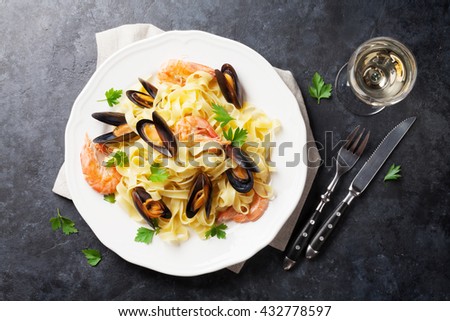 Pasta with seafood and white wine on stone table. Mussels and prawns. Top view
