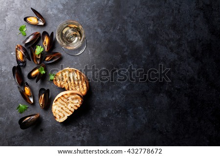 Mussels, bread toasts and white wine on stone table. View with copy space