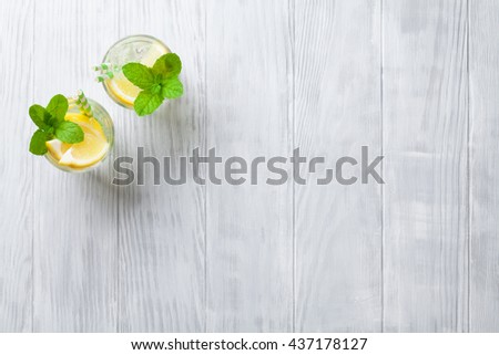 Lemonade glasses with lemon, mint and ice on wooden table. Top view with copy space