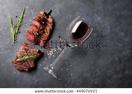Grilled sliced beef steak with balsamico and rosemary and red wine on stone table. Top view with copy space