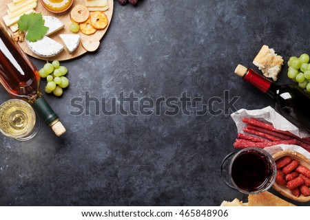 Red and white wine, grape, honey, cheese and sausages over stone table. Top view with copy space