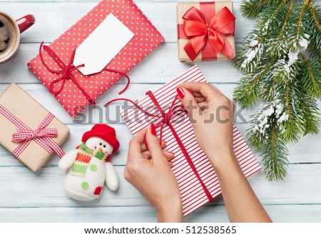 Female hands wrapping christmas gift box above wooden table. Top view