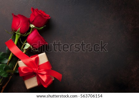 Valentines day greeting card. Red roses and gift box on stone table. Top view with space for your greetings