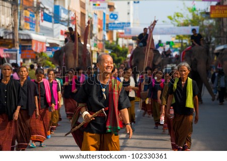 SURIN, ISAN, THAILAND - NOVEMBER 19, 2010: A Surin village elder leads a group of traditional dress villagers in a parade at the annual Surin Elephant Roundup on November 19, 2010 in Surin, Thailand