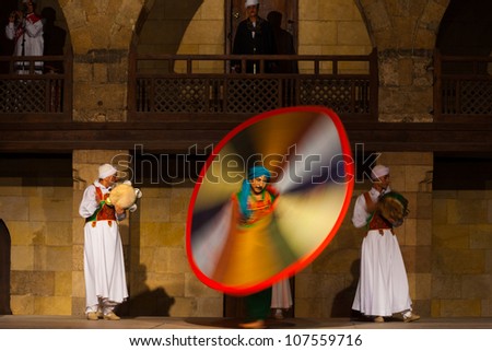 CAIRO, EGYPT - JULY 3: An Egyptian Sufi dancer twirls in a motion blurred whirling dervish at an open air courtyard performance, a famous tourist attraction in Cairo, Egypt on July 3, 2010