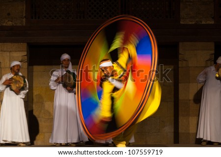 CAIRO, EGYPT - JULY 3: An Egyptian Sufi dancer in yellow spins during a whirling dervish at an open air courtyard performance, a famous tourist attraction in Cairo, Egypt on July 3, 2010