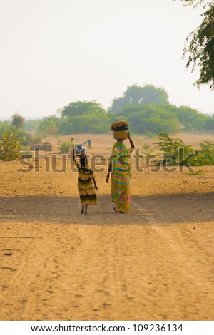 KHURI, INDIA - NOVEMBER 26: An Indian mother and daughter fetch water at the rural community well with balanced jugs in the dry desert climate on November 26, 2009 in Khuri, India