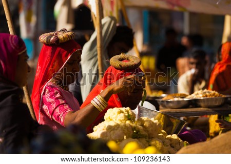 JODHPUR, INDIA - NOVEMBER 29, : Traditional Indian women buy vegetables on market day on November 29, 2009 in Jodhpur, India. Outdoor markets are slowly being replaced by grocery stores in India