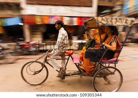 MATHURA, INDIA - NOVEMBER 13,: Two Indian women laugh riding a cycle rickshaw, a popular form of taxi, through a busy bazaar on November 13, 2009 in Mathura, India