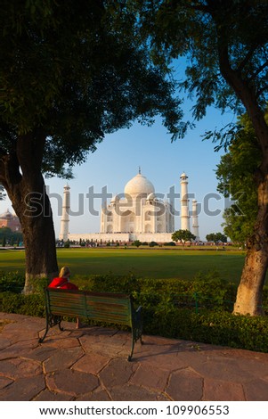 The Taj Mahal framed by the pleasant greenery of shrubs and trees along a footpath in Agra, India