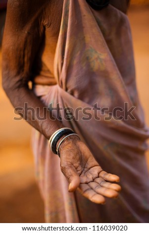 GOKARNA, INDIA - MARCH 9: A poor old Indian senior woman extends her hand and palm to ask for money and change on March 9, 2009 in Gokarna, India