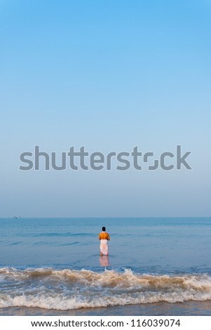 GOKARNA, INDIA - MARCH 2: A hindu man stands in the ocean to pray and offer gifts to Hindu gods in the morning at Gokarna beach, a holy pilgrimage site, on March 2, 2009 in Gokarna, India