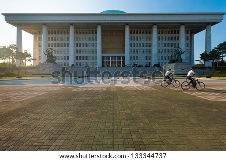 SEOUL, KOREA - SEPTEMBER 8, 2009: Unidentified policemen bicycle in front of the National Assembly building, home to the legislative branch of government, in Seoul, South Korea on September 8, 2009