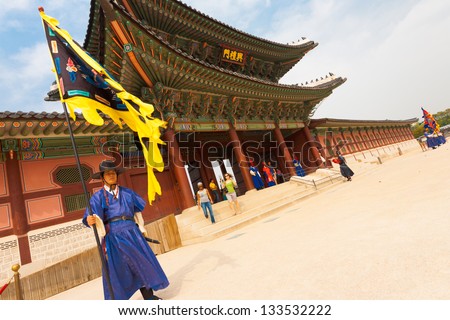 SEOUL, KOREA - SEPTEMBER 17, 2009: A flag guard in ancient blue costume stands at the entry gate of Gyeongbokgung Palace, the old royal residence, in Seoul, South Korea on September 17, 2009. Tilted