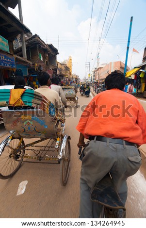VARANASI, INDIA - JANUARY 27, 2008: An unidentified cycle rickshaw, a standard form of Indian transportation, takes passengers to their destination on January 27, 2008 in Varanasi, India