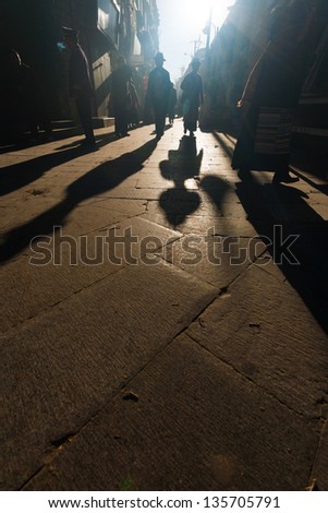 LHASA, CHINA - OCTOBER 17: Tibetan people in traditional clothes walk the Barkhor circuit, a famous tourist, pilgrimage destination in Tibet on October 17, 2007 in Lhasa, China. Low angle