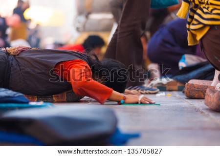 LHASA, CHINA - OCTOBER 17: An unidentified Tibetan prostrator lies flat on her stomach at Jokhang temple, a famous tourist, pilgrimage site in Tibet on October 17, 2007 in Lhasa, China