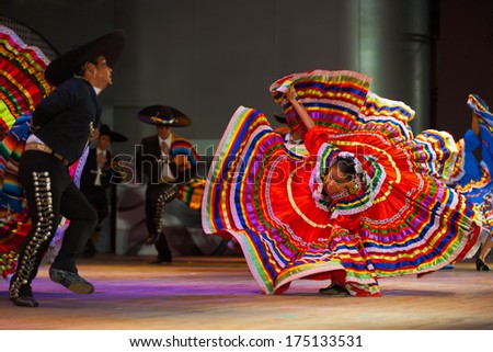 SEOUL, KOREA - SEPTEMBER 30, 2009: A female Mexican dancer spins her colorful traditional dress in front of her partner at a traditional folkloric dance performance at city hall\'s open-air stage