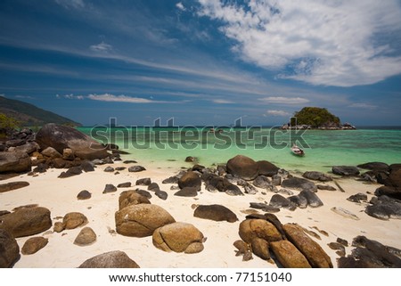 A rocky sand beach and beautiful coral is seen through the crystal clear water of island paradise, Koh Lipe (aka Ko Lipeh) in Thailand.