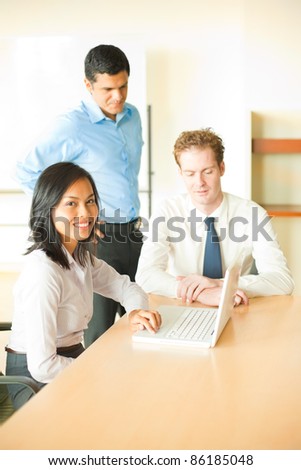 A beautiful Asian female leads a business meeting with her male colleagues