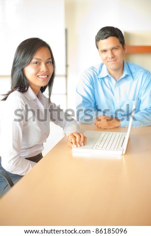 A beautiful Asian businesswoman meets with a handsome hispanic businessman