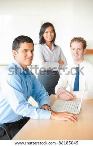 A latino man leads a business meeting with two colleagues