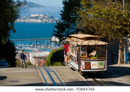 SAN FRANCISCO, USA - SEPT. 21:  Tourists ride the cable car on a sunny day at the top of Hyde Street overlooking Alcatraz in San Francisco September 21, 2011 in San Francisco, USA