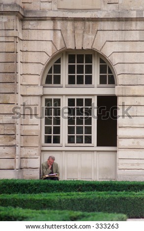 Man sitting reading outside a building in Paris, France,
