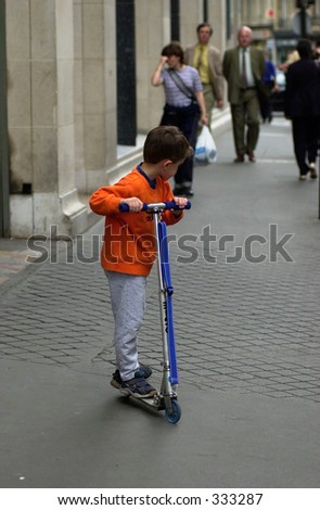 Young boy playing with a scooter on the side walk in Paris, France,