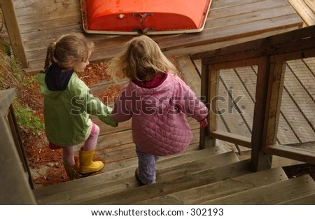 Two young girls climbing down a flight of wooden stairs,