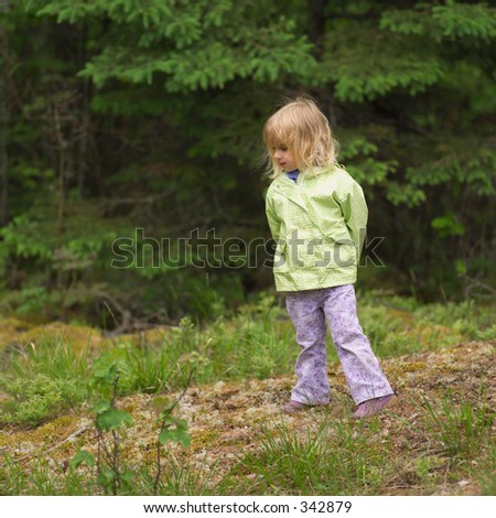 Young girl standing in the woods with her hands behind her back,