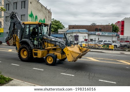 NEW YORK - JUNE 11: backhoe loader on June 11, 2014 in NY. A backhoe loader is a heavy equipment vehicle that has a tractor like unit with a shovel/bucket on the front and a small backhoe on the back.
