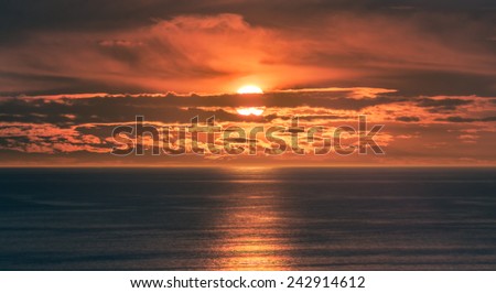 Sunset or Sunrise over Ocean - Orange Sun Setting or Sun Rising on Water with Beautiful Clouds in Pretty Sky