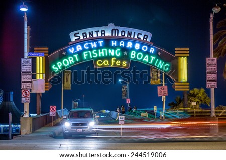 SANTA MONICA - JAN 14, 2015: Santa Monica Pier Sign on Ocean Avenue in LA California at Night on Colorado Avenue with Car Exiting. Santa Monica is a beachfront city in Los Angeles California.