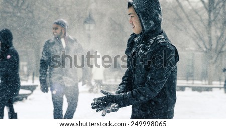 NEW YORK - JAN 26, 2015: Asian man in blizzard wiping snow off gloves in Washington Square Park in Manhattan New York. The nor\'easter snowstorm of 2015 was named Juno.