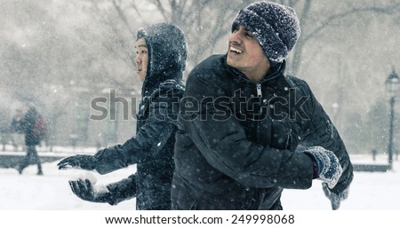NEW YORK - JAN 26, 2015: Asian and Indian man throwing snow ball in snowball fight in blizzard in Washington Square Park in Manhattan New York. The nor\'easter snowstorm of 2015 was named Juno.